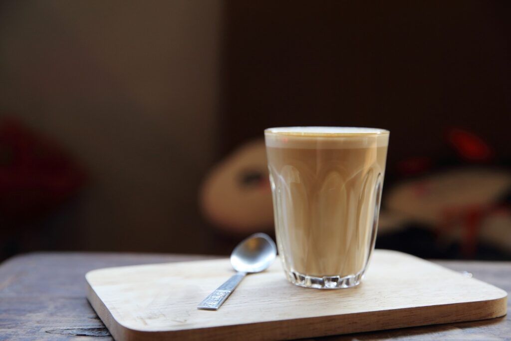Glass of caffè latte placed on a wooden board