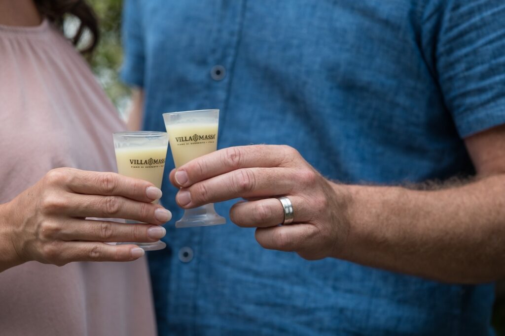 Two people holding glasses of creamy Italian beverage Limoncello liqueur