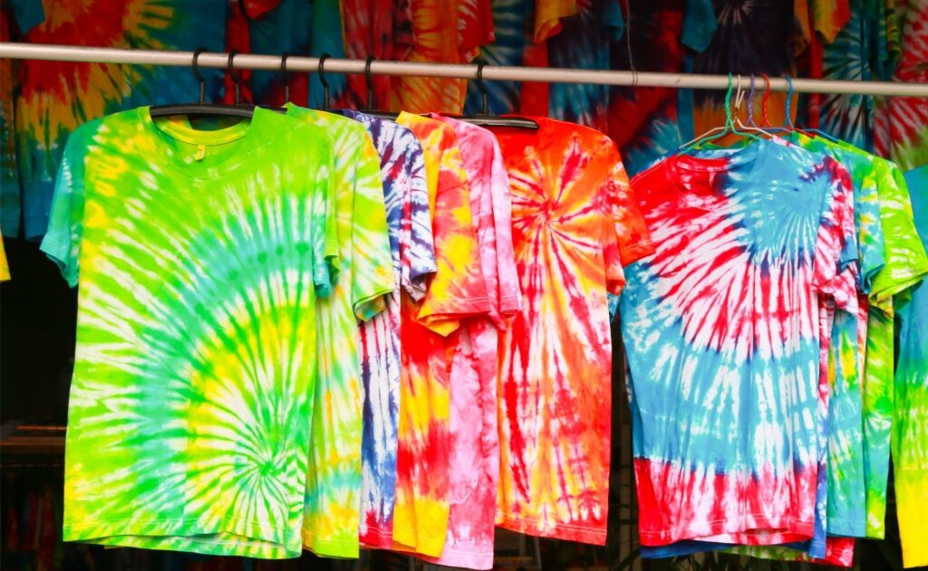 Brightly colored tie-dye shirts hanging in a market