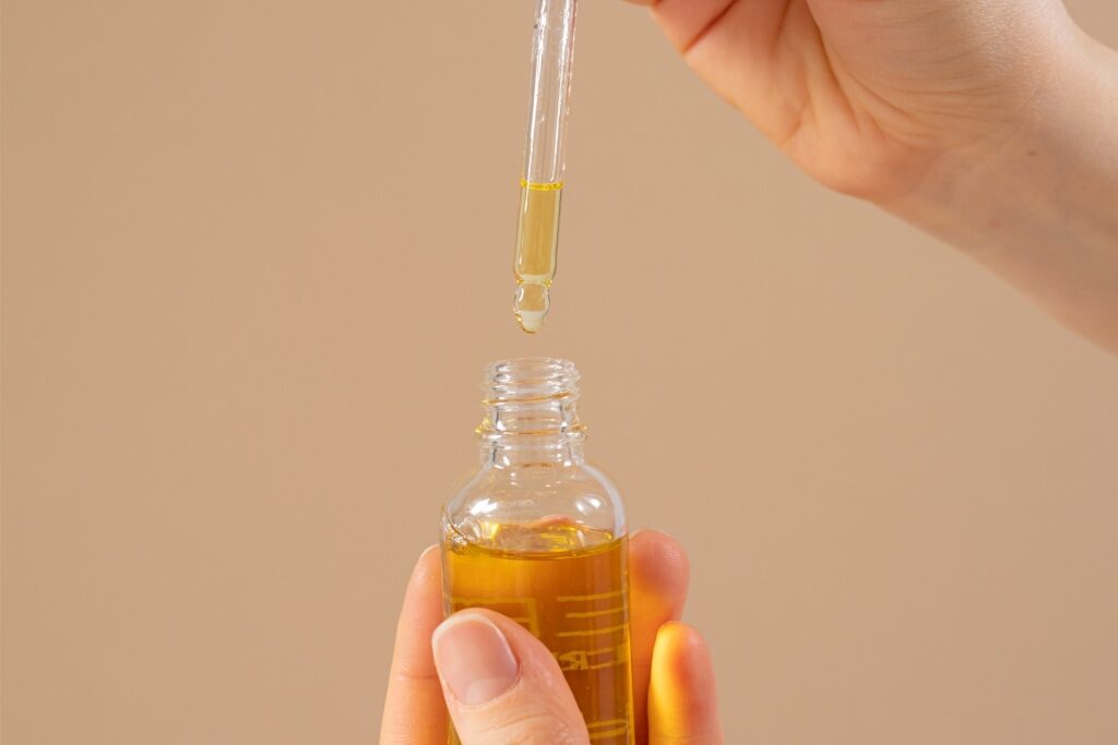 Close-up of castor oil in a small container with dropper