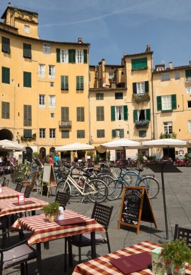 Historic square Piazza dell'Anfiteatro featuring colorful cafés and al fresco tables