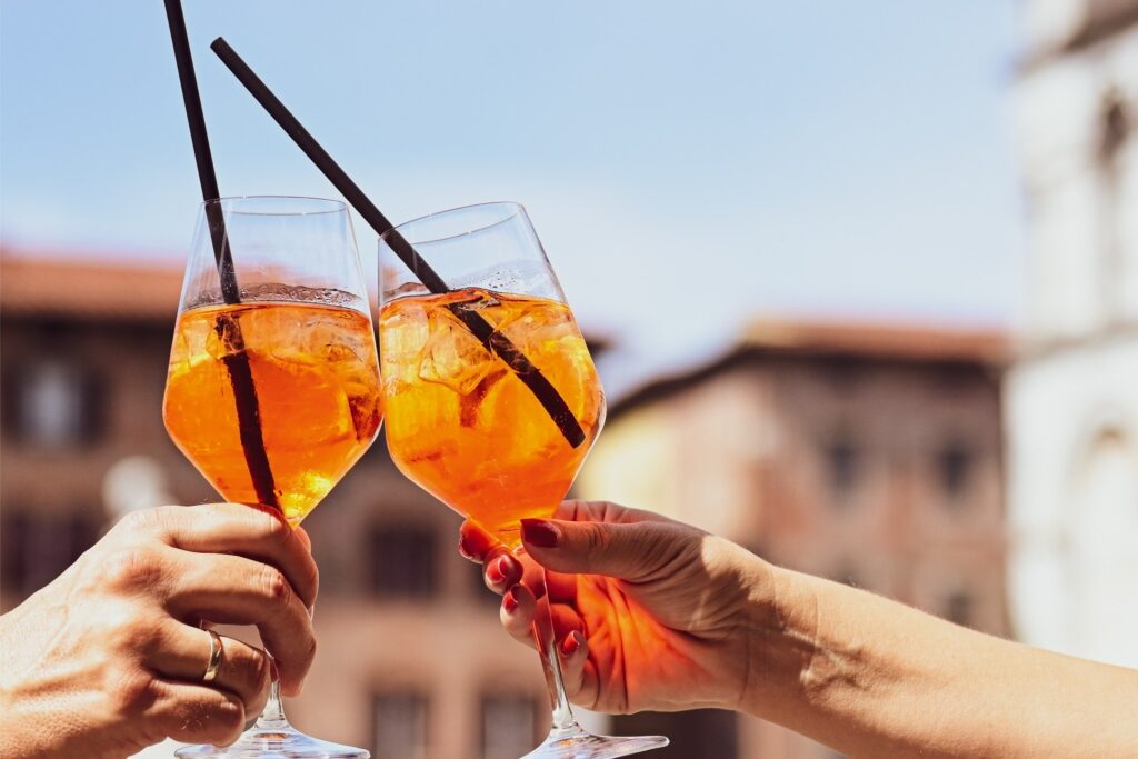 Cheers with Aperol Spritz in a small Italian square in Lucca, Tuscany