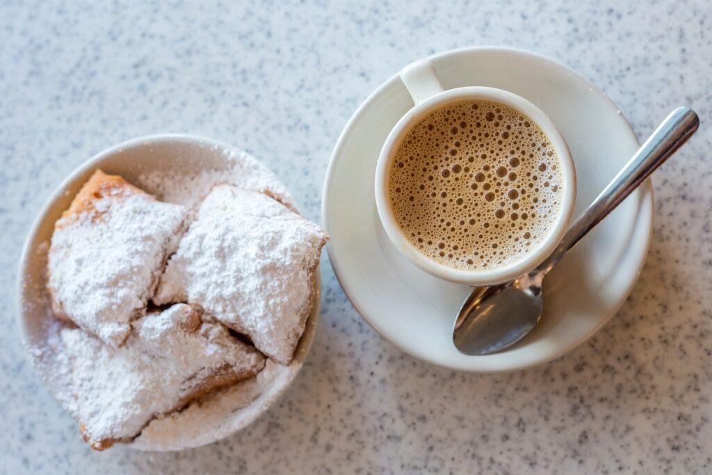 Cup of Café du Monde coffee served with powdered sugar beignets in New Orleans