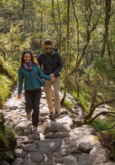 Couple trekking along a rocky trail leading toward Pulpit Rock in Norway