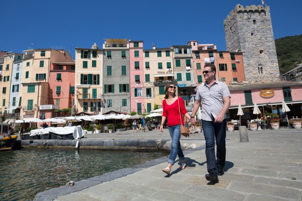 Tourist couple with colorful buildings of Porto Venere, Italy in the background