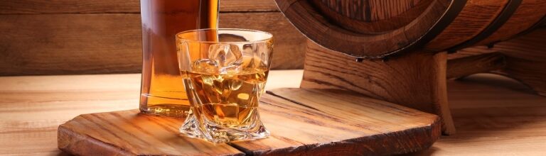 Rich amber Irish whiskey in a glass alongside its bottle