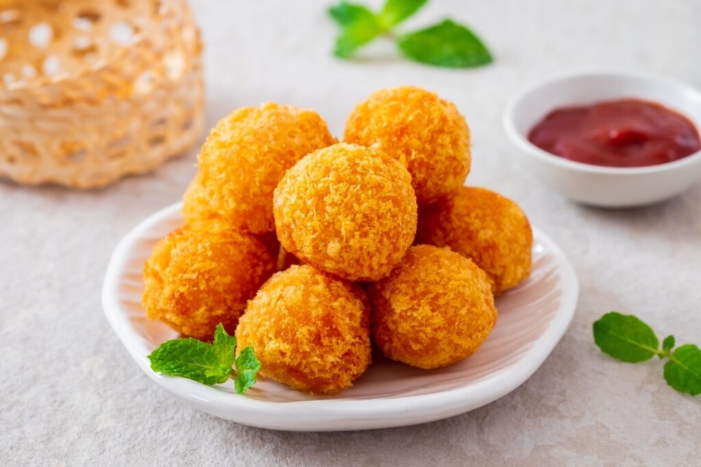 Deep-fried cheese balls on a plate with ketchup