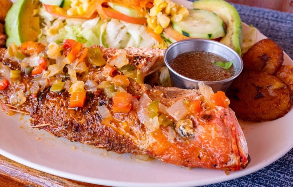 Caribbean Creole-style fish meal with avocado, salad, and plantains