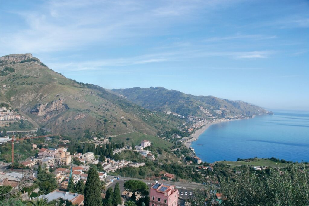 Messina’s coastline with blue waters and city buildings along the shore