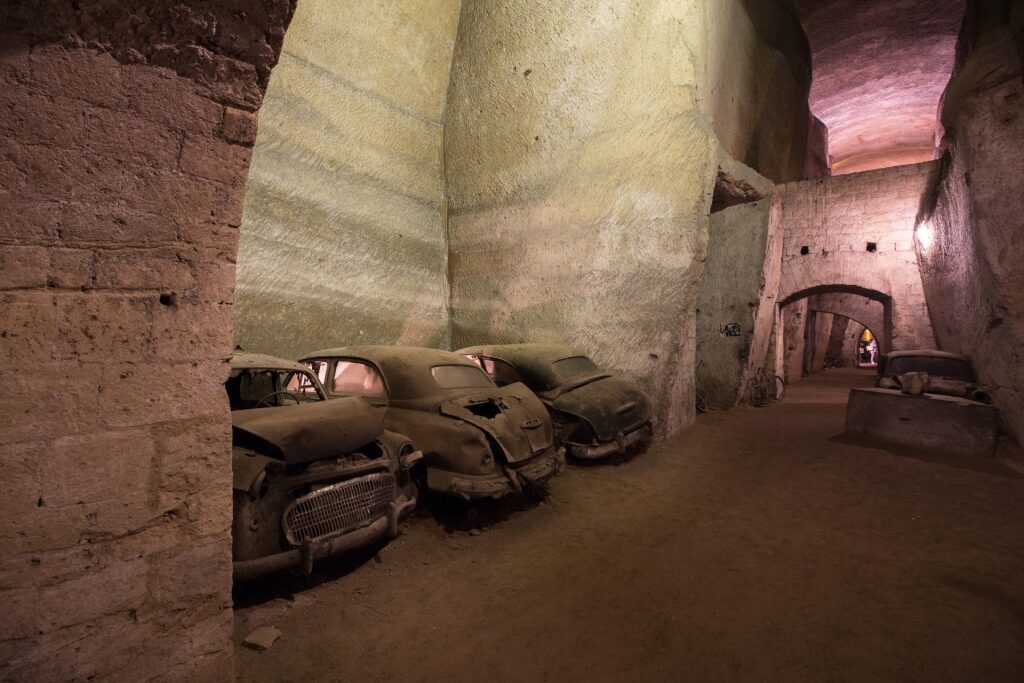 Abandoned vehicles inside the historic Galleria Borbonica tunnels of Naples