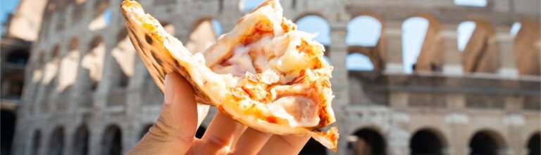 Hand holding a slice of Italian pizza with the Colosseum in the background
