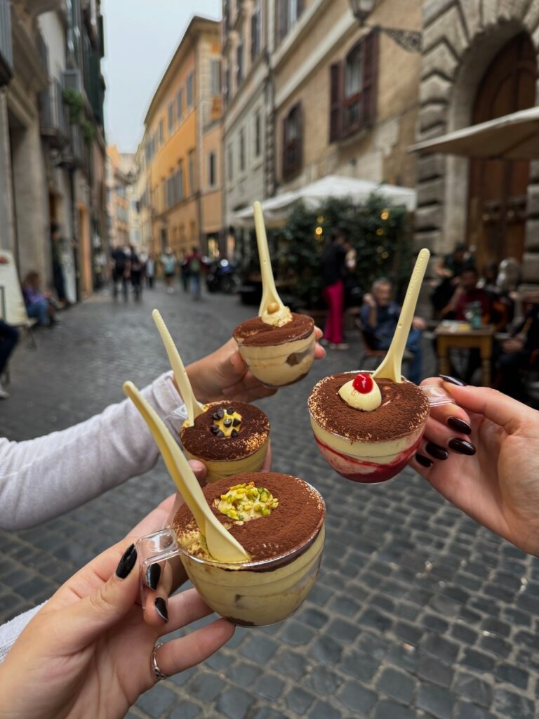 Hands holding cups of tiramisu dessert in Rome