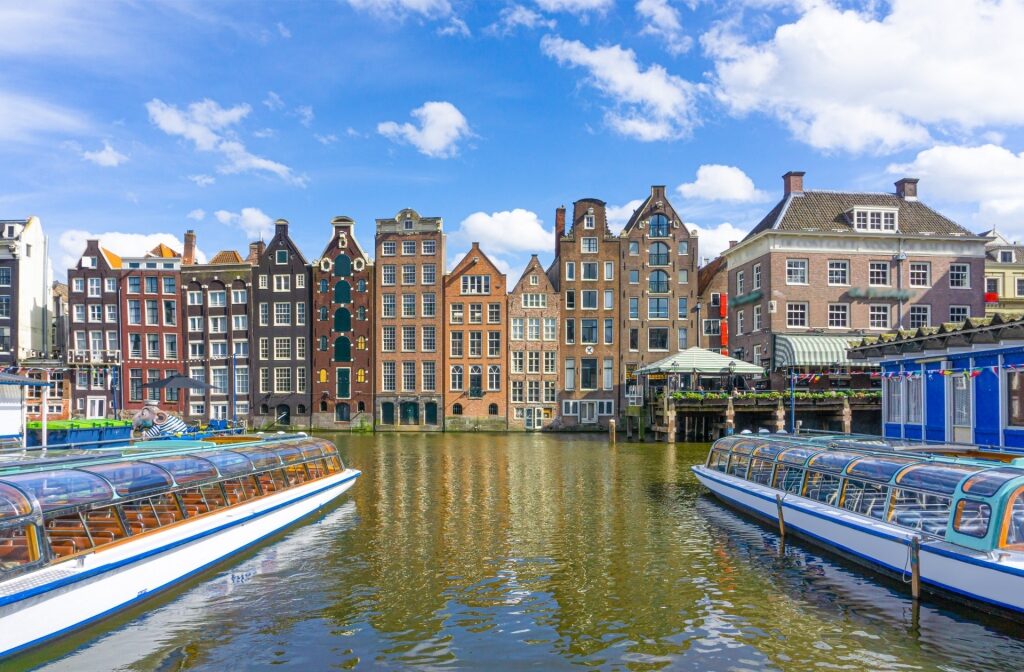 View of Amsterdam canal with waterfront buildings and tour boats