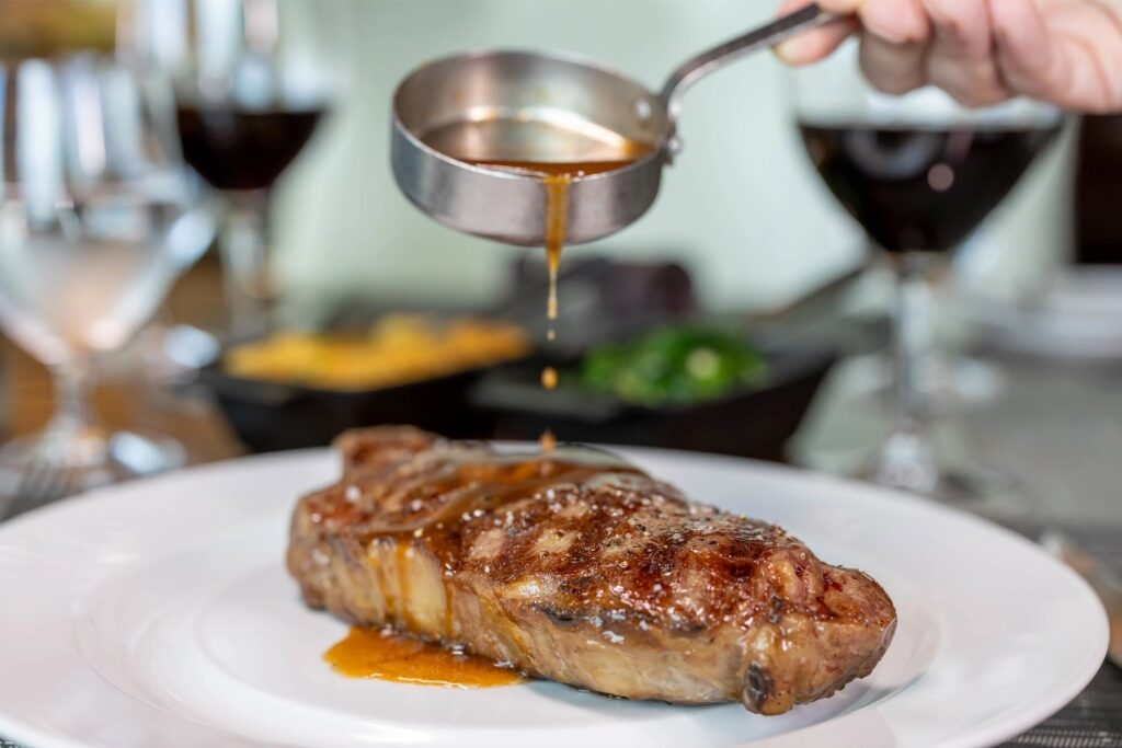 Steak served with sauce being poured over it