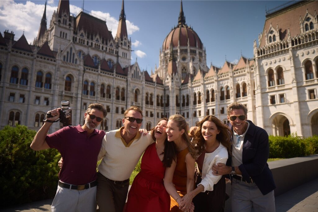 Tourists pose for a photo in front of the ornate Hungarian Parliament Building in Budapest