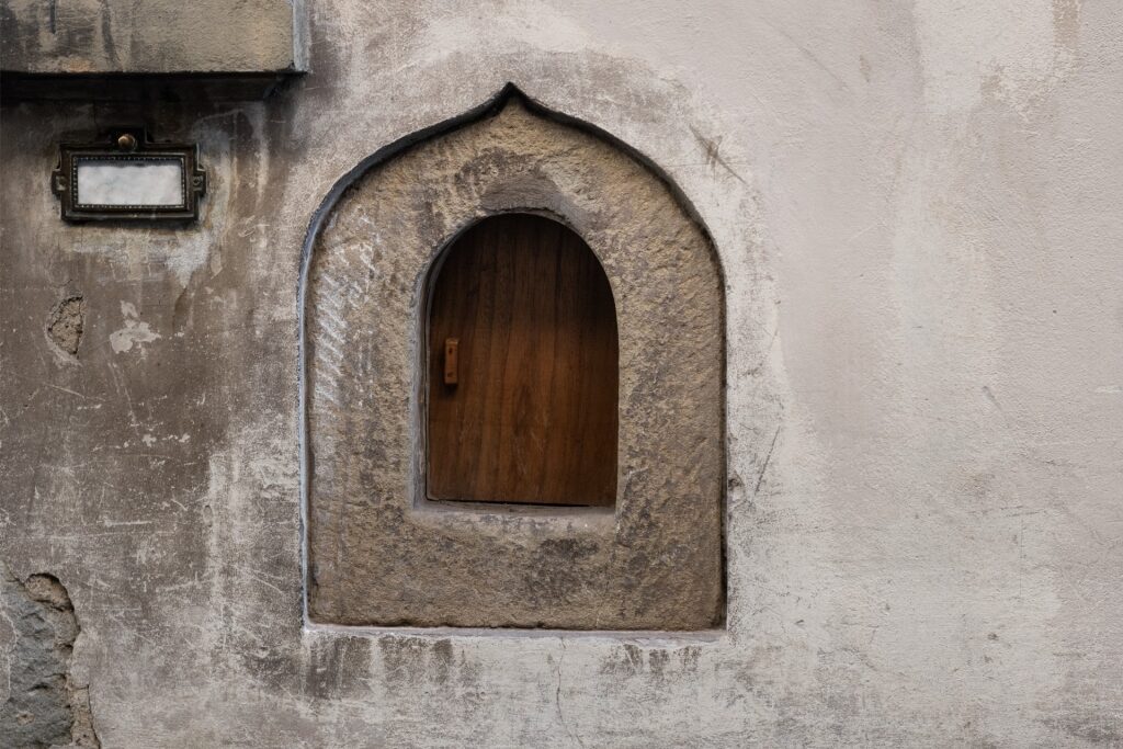 Historic Florentine wine window, or buchetta del vino, on a stone wall
