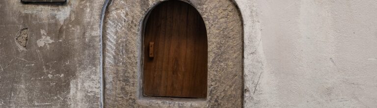 Historic Florentine wine window, or buchetta del vino, on a stone wall