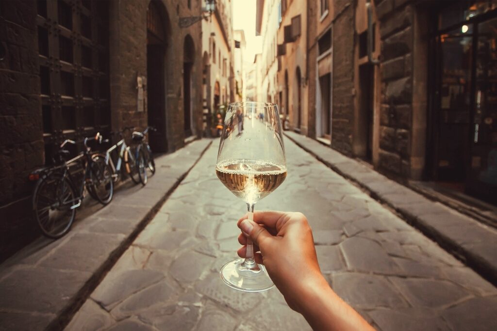 Glass of white wine raised in a Florentine alley