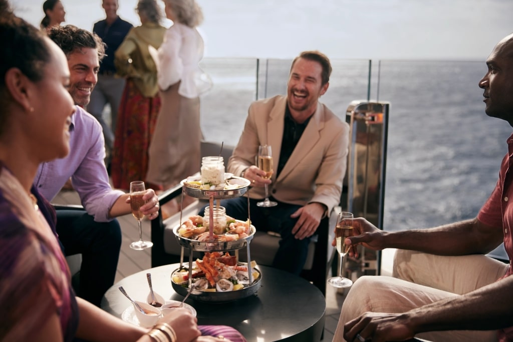A group of friends enjoying food and champagne on Celebrity Ascent.