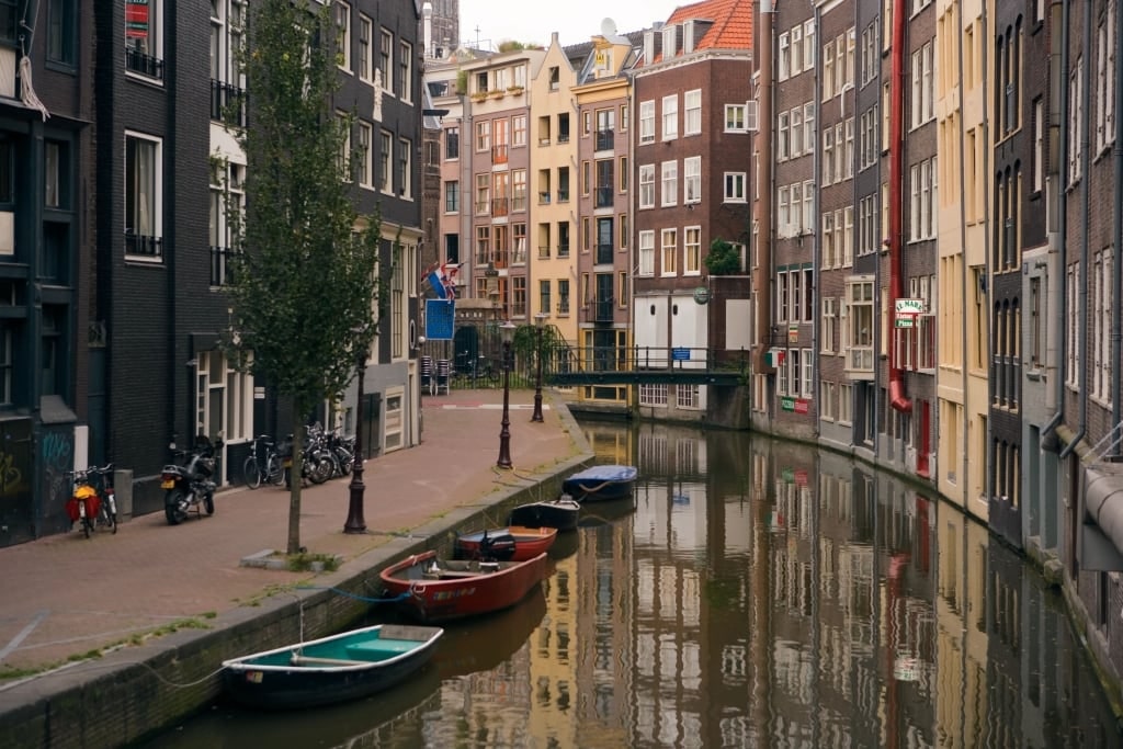 Wide Amsterdam canal waters reflecting historic canal-lined streets and numerous bicycles inspiring romantic Rhine River port experiences.