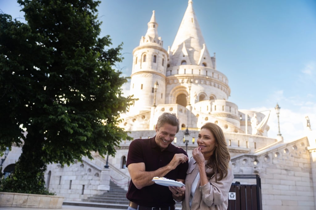 A happy couple explores the ornate white stone arches of historic Fisherman’s Bastion