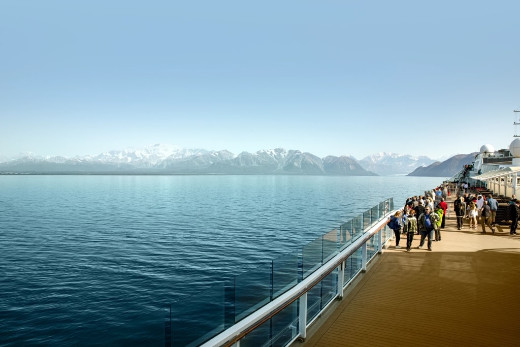 Passengers enjoying scenic sailing past the majestic snow-capped peaks of the St. Elias Mountain Range near Hubbard Glacier in Alaska.