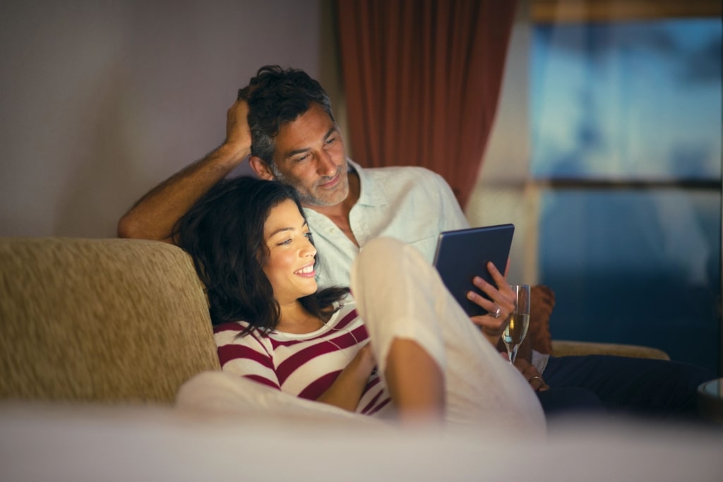 A smiling couple uses a tablet to plan future travel. 