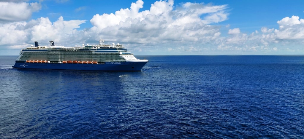 Elegant Celebrity Solstice cruise ship upper pool deck featuring lounge chairs alongside manicured lawns.