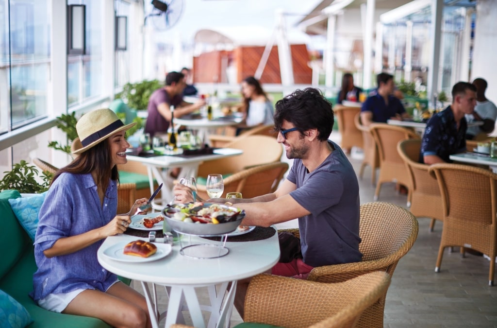 Smiling couple shares fresh cruise ship restaurant lunch dishes.