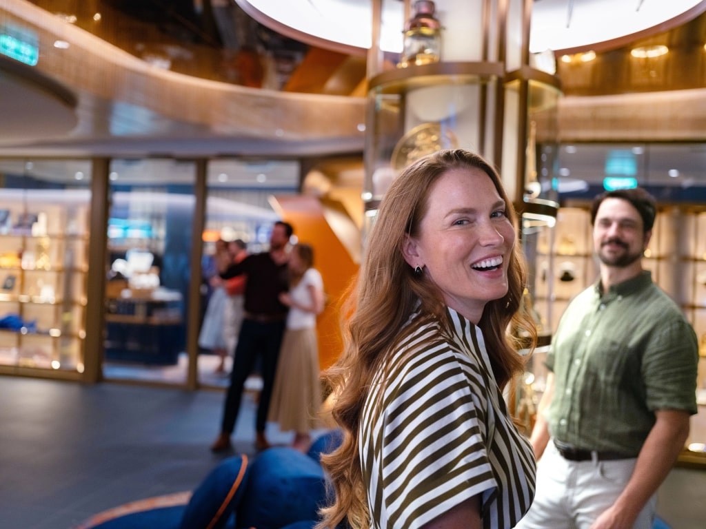 Smiling woman exploring a sophisticated luxury cruise ship hall environment.
