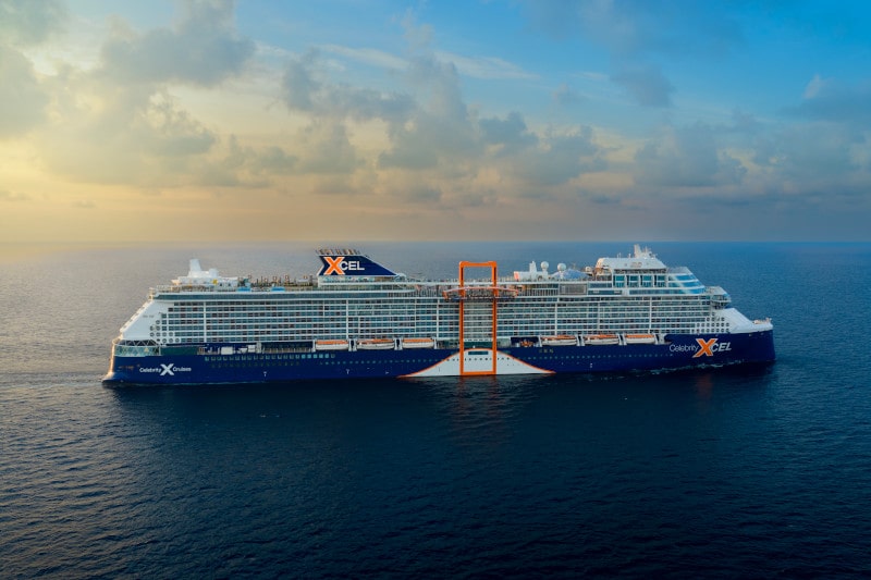 Massive Celebrity Edge cruise ship navigating calm deep blue open ocean waters daytime.