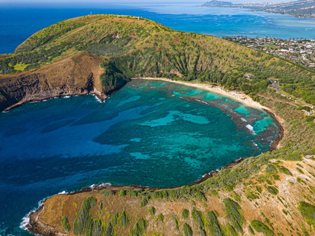 Vibrant O'ahu tropical coastline displaying crashing blue Pacific Ocean waves alongside sunlit green headlands.
