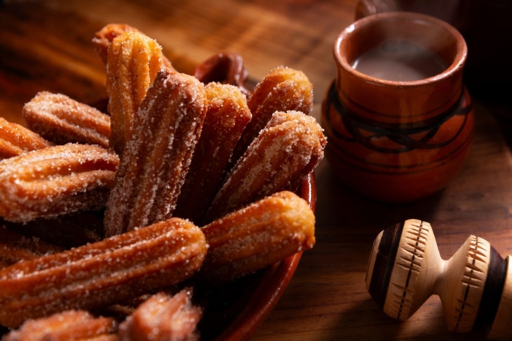 Golden, crispy Mexican churros dusted with sweet cinnamon sugar sit beside rich chocolate dipping sauce.