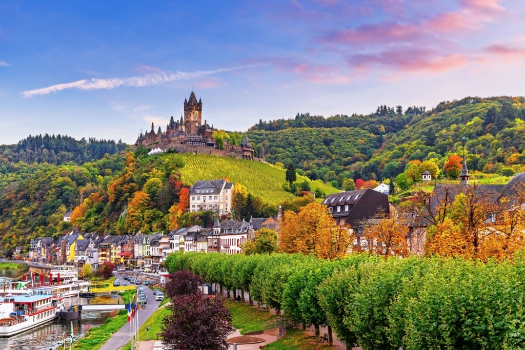 Hilltop Reichsburg Castle and colorful buildings gracing the Cochem, Germany, riverfront.