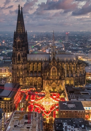 Cologne, Germany - Dec 14, 2025 : Aerial view of the Cologne Cathedral Christmas Market (Weihnachtsmarkt am Kölner Dom) on Roncalliplatz at sunset - Holiday celebrations in Germany