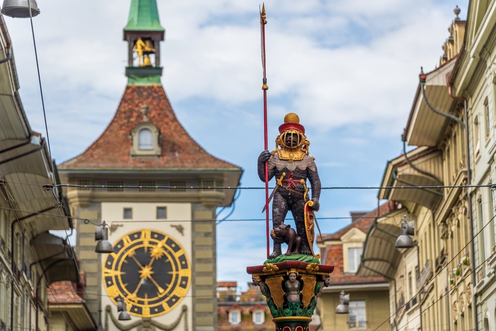 Zahringerbrunnen bear fountain statue with Zytglogge clock tower in the background at Bern, Switzerland
