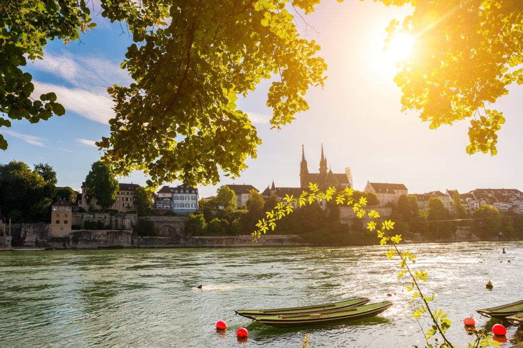 Basel Minister's twin spires and moored boats gracing the sunlit Rhine River. 