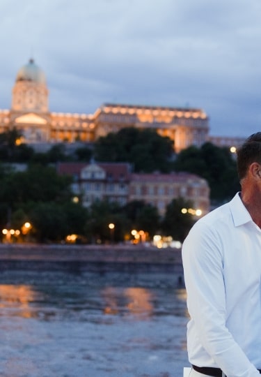 A smiling couple shares a sweet moment before the Hungarian Parliament in Budapest.