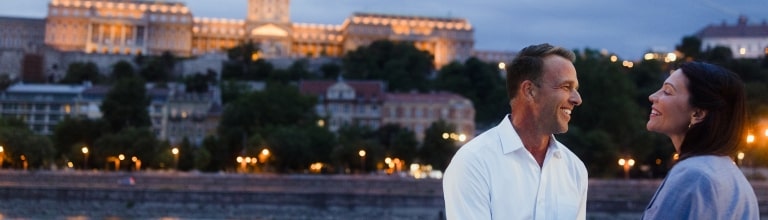 A smiling couple shares a sweet moment before the Hungarian Parliament in Budapest.