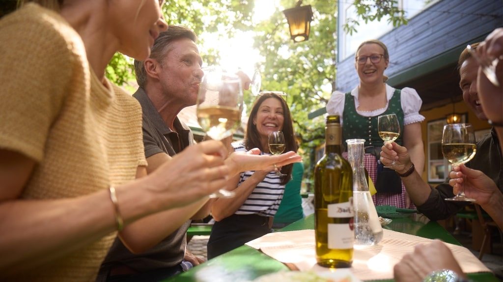 Smiling friends enjoying a glass of white wine.