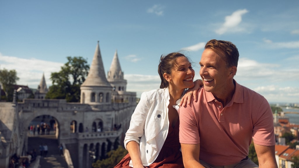 A smiling couple shares a sweet moment before the stone towers of Fisherman’s Bastion.