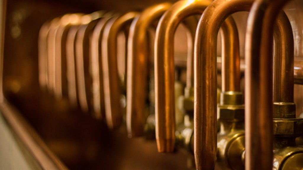 A close-up of polished copper beer taps lined up inside U Vejvodu in Prague.