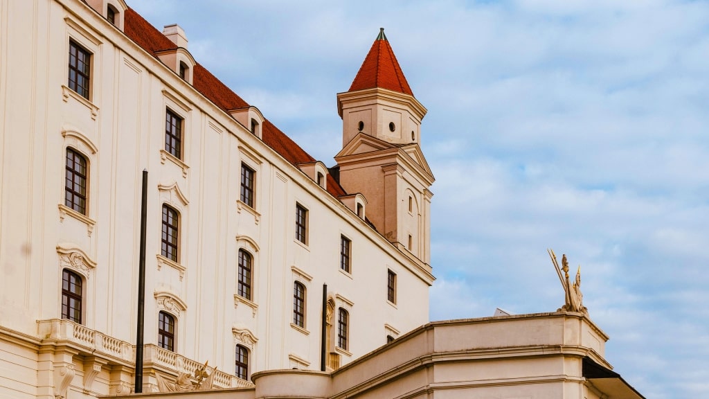 The striking white facade and red-roofed towers of historic Bratislava Castle in Slovakia.