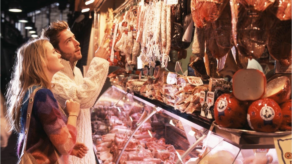 Shopping for authentic, local delicacies at a vibrant European meat and cheese counter.