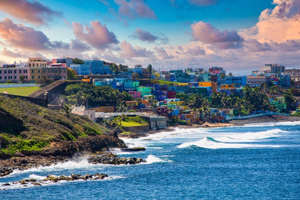Vibrant La Perla neighborhood structures flank a rocky Old San Juan coastline framing ocean waves.