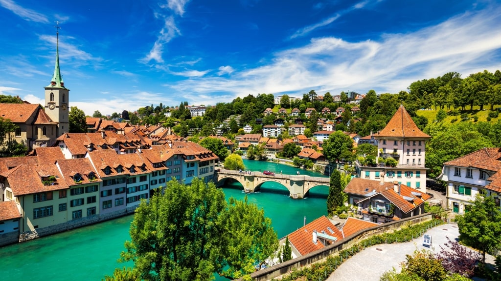 Turquoise Aare River encircles historic Bern's Old City red-roofed buildings showcasing the cathedral spire.
