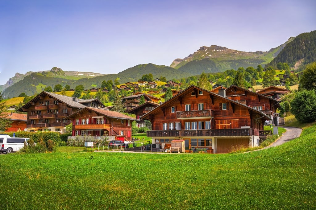Traditional wooden chalets dot the lush green meadows of Grindelwald against a backdrop of soaring Alpine peaks.