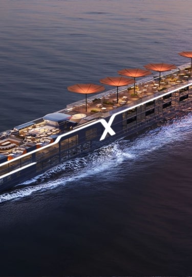 Aerial view of the illuminated Celebrity Compass river ship at dusk.