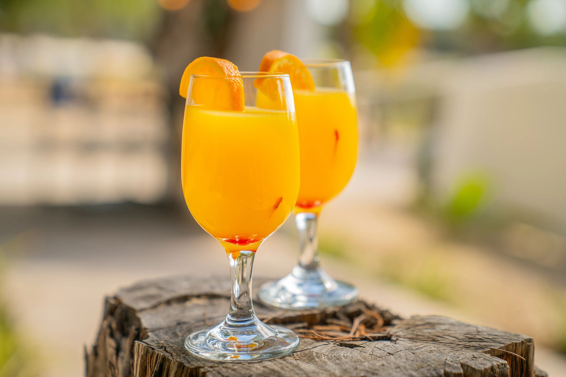 A pair of vibrant Nassau drinks, elegantly decorated with citrus wedges, rest on a sun-drenched table.