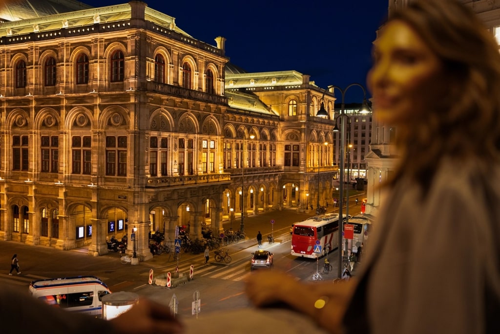 A guest gazes at the radiant facade of the Wiener Staatsoper after sunset.